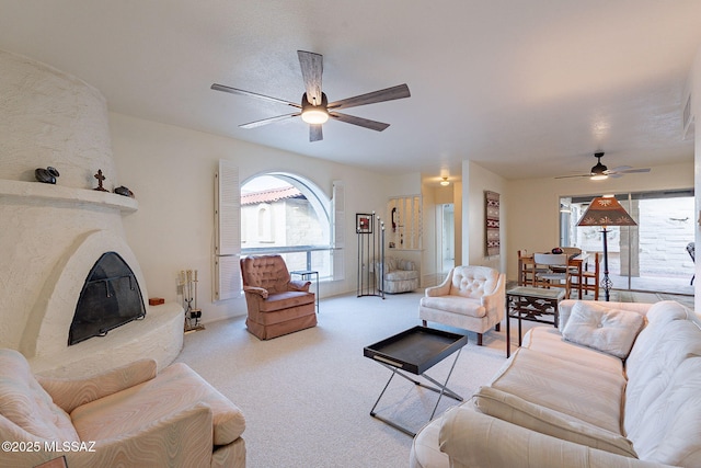 carpeted living room with a ceiling fan and a fireplace