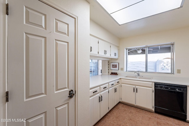 kitchen featuring a skylight, light countertops, white cabinetry, a sink, and dishwasher