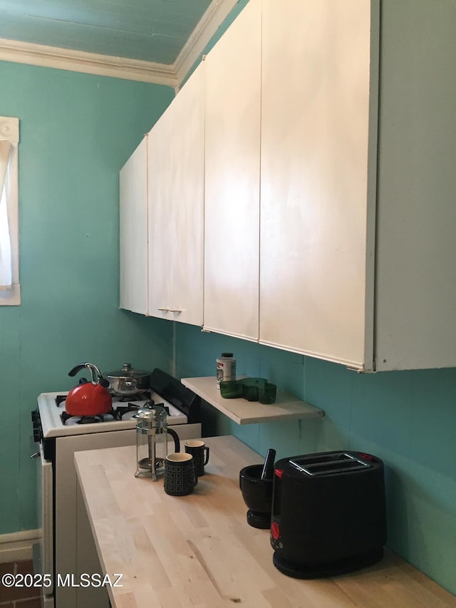 interior space featuring light countertops, gas range oven, and crown molding