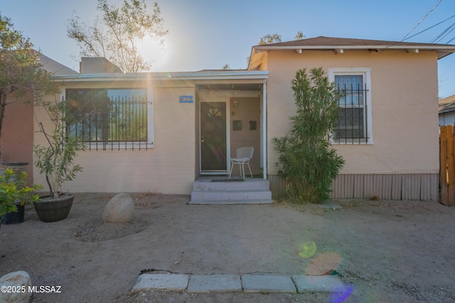 view of front of house with stucco siding and fence