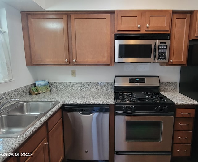 kitchen with light countertops, brown cabinetry, appliances with stainless steel finishes, and a sink