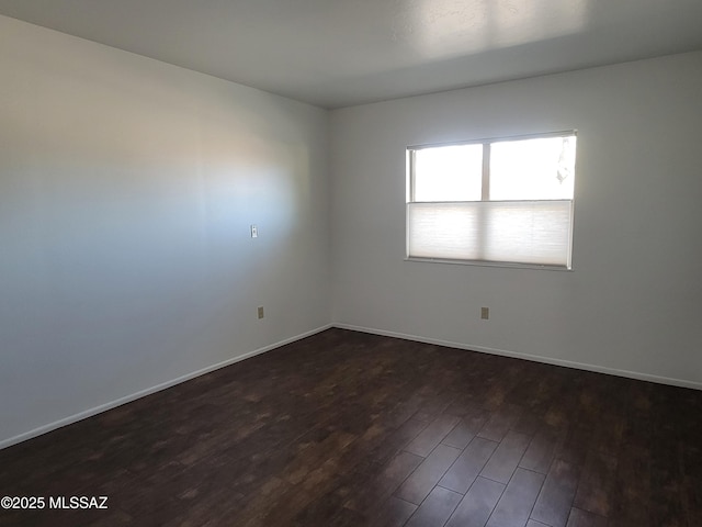 unfurnished room with dark wood finished floors and baseboards