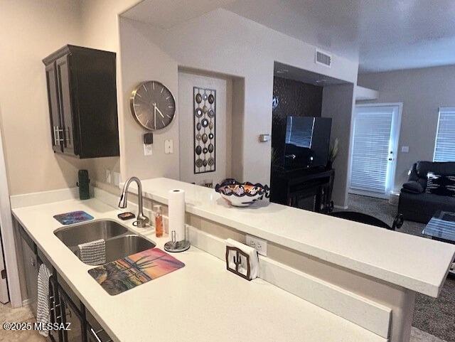 kitchen featuring a sink, visible vents, a peninsula, and light countertops