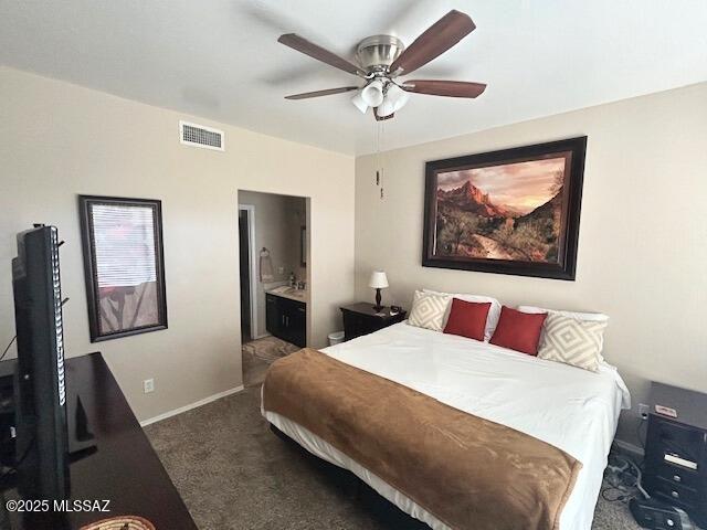 bedroom featuring baseboards, visible vents, ensuite bath, ceiling fan, and dark carpet