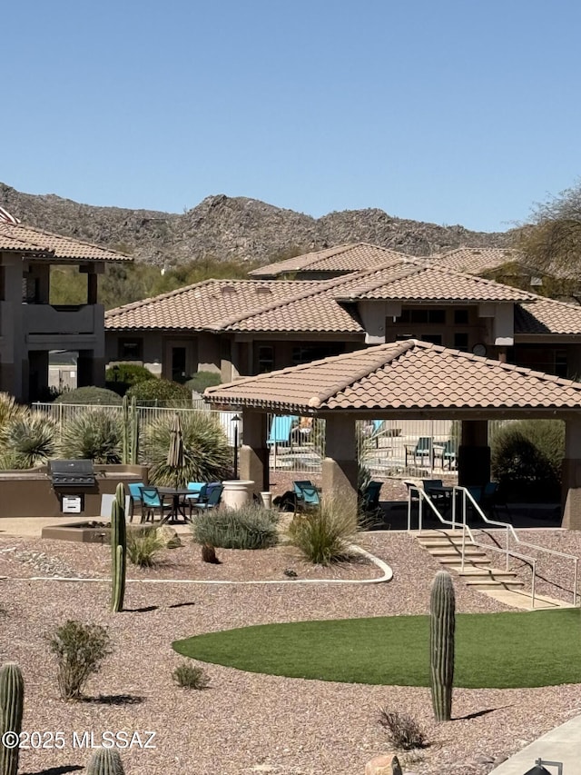 rear view of house featuring a mountain view, stucco siding, and a tiled roof