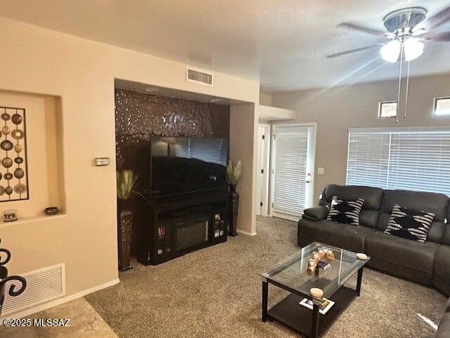 carpeted living room with a ceiling fan, visible vents, and baseboards