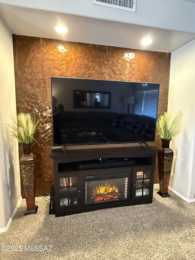 interior details featuring visible vents, baseboards, a glass covered fireplace, and carpet flooring