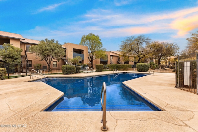 community pool with a patio area and fence