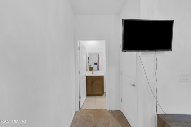 corridor with a sink and light carpet