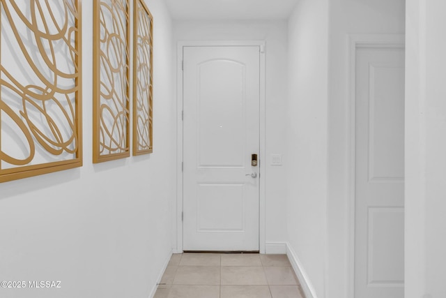 doorway with light tile patterned floors and baseboards