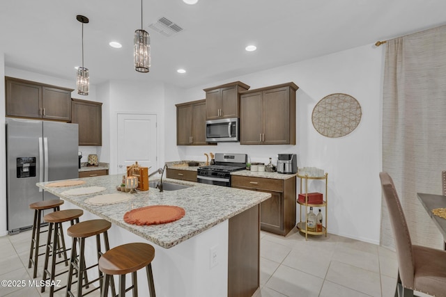 kitchen with visible vents, a breakfast bar, appliances with stainless steel finishes, light tile patterned flooring, and a sink