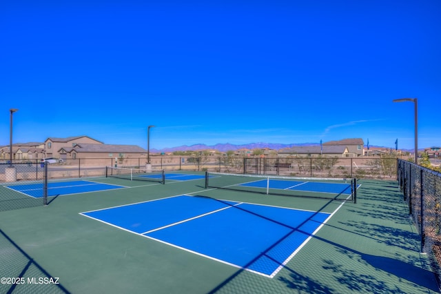 view of tennis court with community basketball court, a mountain view, and fence