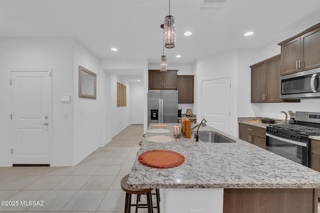kitchen with light tile patterned floors, visible vents, a sink, dark brown cabinetry, and appliances with stainless steel finishes