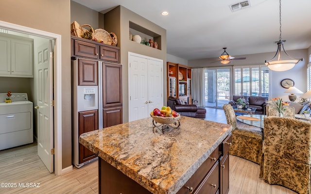 5084 W Desert Poppy Ln, Marana, AZ 85658 - kitchen with visible vents, washer / clothes dryer, a ceiling fan, light wood-style floors, and a center island