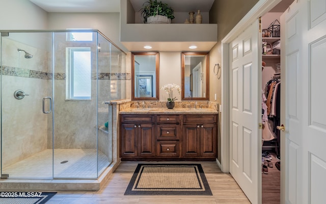 5084 W Desert Poppy Ln, Marana, AZ 85658 - full bathroom featuring a stall shower, double vanity, wood finished floors, and a sink