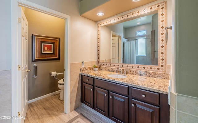 5084 W Desert Poppy Ln, Marana, AZ 85658 - full bathroom with tile walls, toilet, wood finished floors, recessed lighting, and vanity