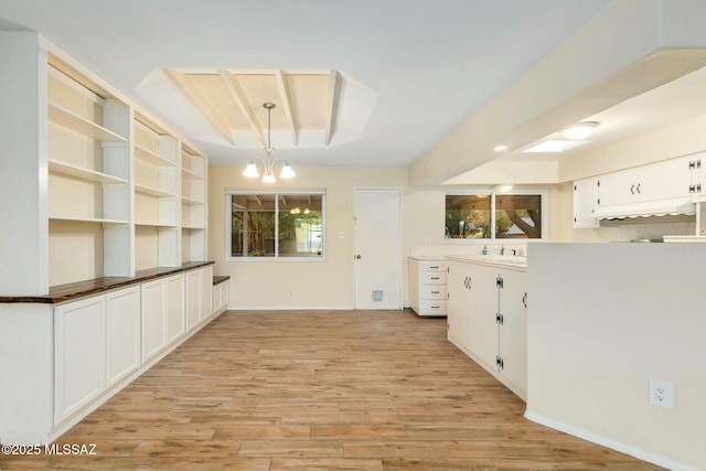 interior space with a healthy amount of sunlight, a sink, light wood-style flooring, and an inviting chandelier