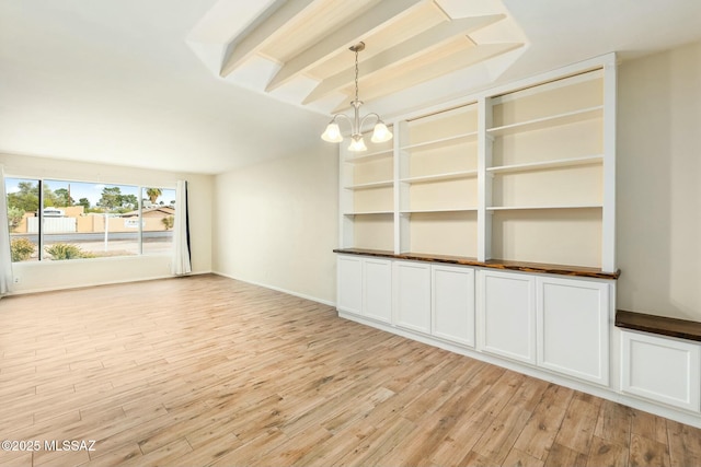 unfurnished room featuring baseboards, light wood finished floors, beam ceiling, and a notable chandelier