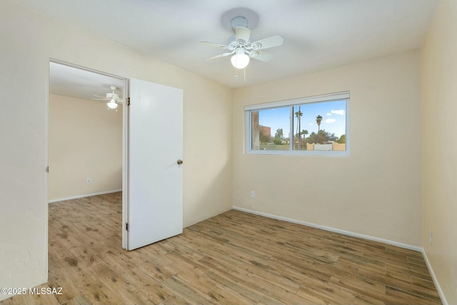 empty room with baseboards, a ceiling fan, and wood finished floors