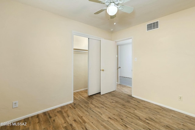 unfurnished bedroom with baseboards, visible vents, ceiling fan, wood finished floors, and a closet