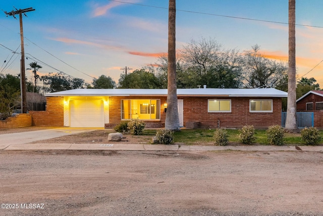 ranch-style house featuring concrete driveway, brick siding, fence, and an attached garage