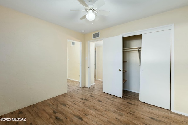 unfurnished bedroom featuring a ceiling fan, a closet, visible vents, and wood finished floors