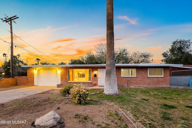 view of front of property featuring brick siding, a yard, concrete driveway, fence, and a garage