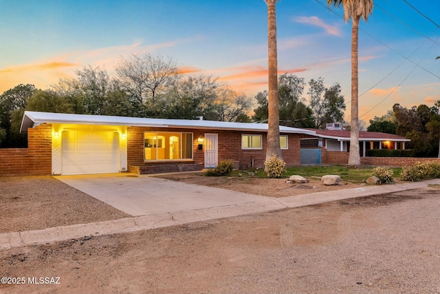 view of front of property with a garage, driveway, brick siding, and fence