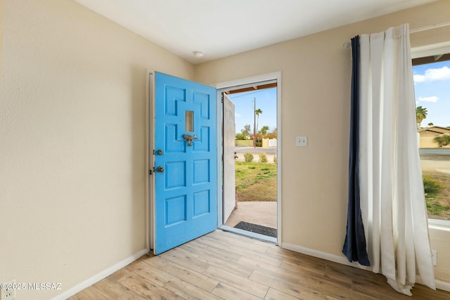 entryway with a healthy amount of sunlight, light wood-style flooring, and baseboards