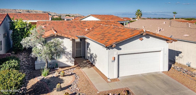 view of front of home featuring a tile roof, driveway, an attached garage, and stucco siding