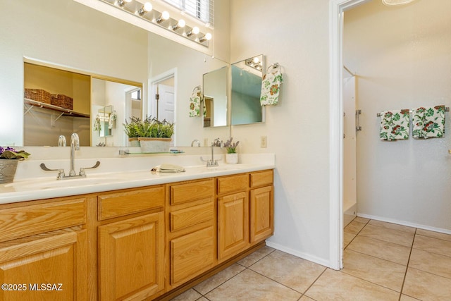 bathroom with tile patterned flooring, a sink, baseboards, and double vanity