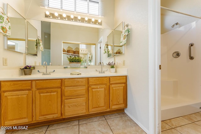 full bathroom featuring double vanity, a sink, a shower stall, baseboards, and tile patterned floors