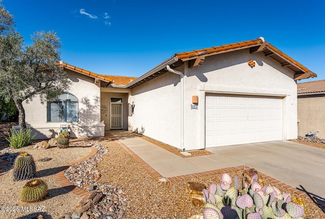 view of front of home featuring concrete driveway, an attached garage, a tiled roof, and stucco siding