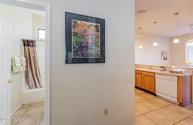 kitchen featuring decorative light fixtures, visible vents, light tile patterned flooring, a sink, and dishwasher