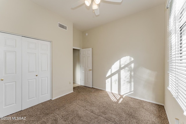 unfurnished bedroom featuring multiple windows, a closet, carpet flooring, and visible vents