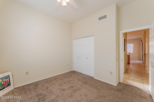 unfurnished bedroom with light carpet, light tile patterned floors, baseboards, visible vents, and a closet