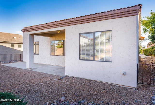 exterior space featuring a patio, fence, and stucco siding