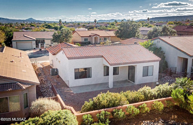 exterior space featuring a patio, a mountain view, central AC, a residential view, and stucco siding