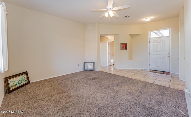 unfurnished living room with light carpet, light tile patterned floors, visible vents, and a ceiling fan