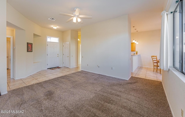 carpeted entryway featuring tile patterned flooring, visible vents, and a ceiling fan