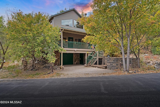 view of front of property with stairway, an attached garage, stone siding, and driveway