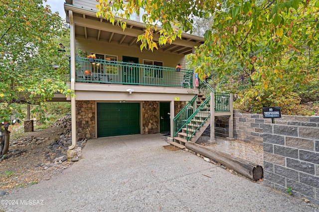 view of front of home featuring a garage, stone siding, driveway, and stairs