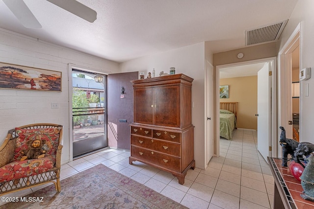 interior space with light tile patterned floors, a ceiling fan, visible vents, and a textured ceiling