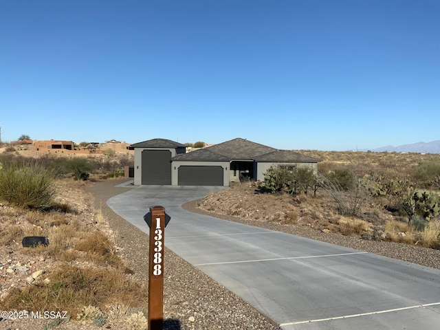 view of front facade featuring a garage, a mountain view, driveway, and stucco siding