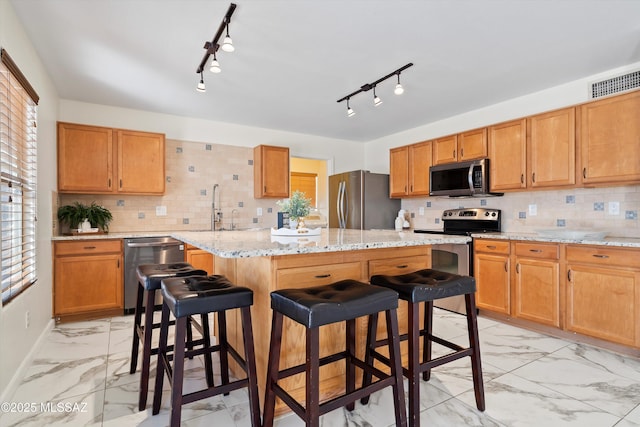 kitchen featuring a breakfast bar, marble finish floor, stainless steel appliances, a kitchen island, and a sink