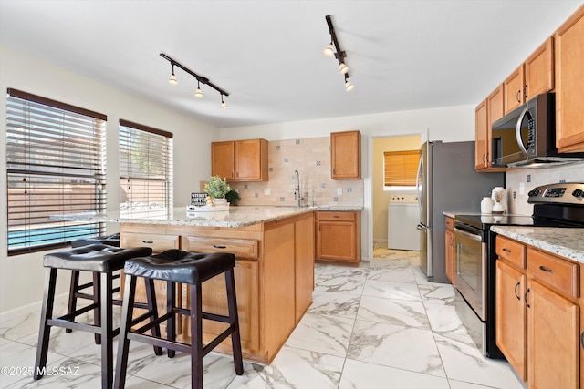 kitchen featuring electric stove, a kitchen island, washer / clothes dryer, marble finish floor, and a sink