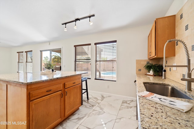 kitchen with tasteful backsplash, marble finish floor, baseboards, and light stone countertops