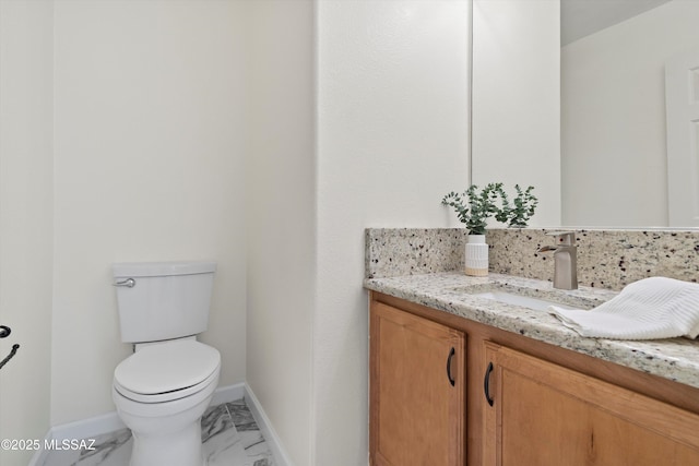 half bath featuring marble finish floor, vanity, toilet, and baseboards