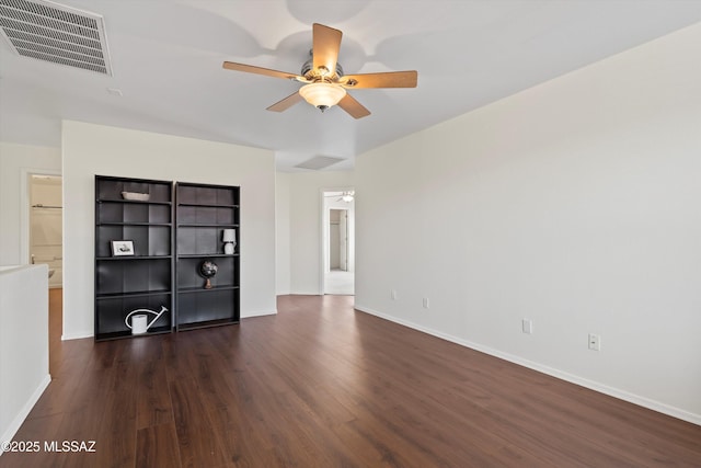 spare room featuring dark wood-type flooring, visible vents, baseboards, and a ceiling fan