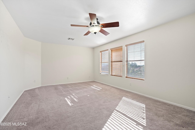 empty room with baseboards, visible vents, a ceiling fan, and light colored carpet